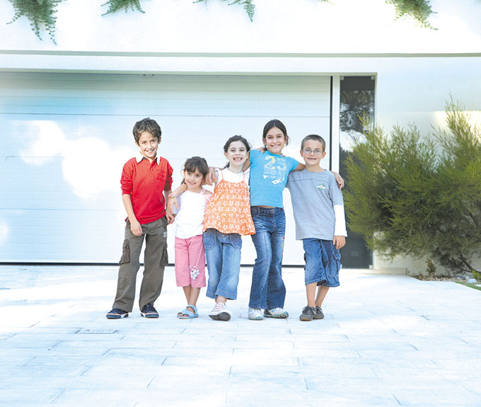 Group of children (5-10) standing in front of garage door, portrait